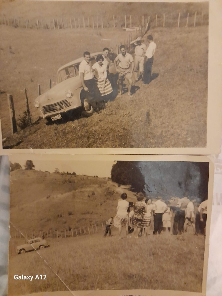 Rural land, fence surrounds. car - Minor Morris leaded to the fence. Six people standing on the right side of the car. 